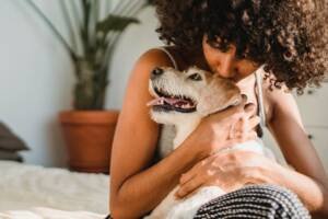 a girl with curly hair hugging her small white dog