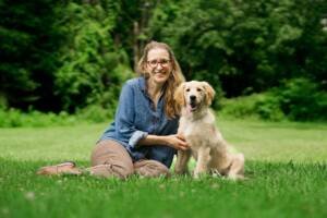 dog trainer sittimg with golden retriever in park